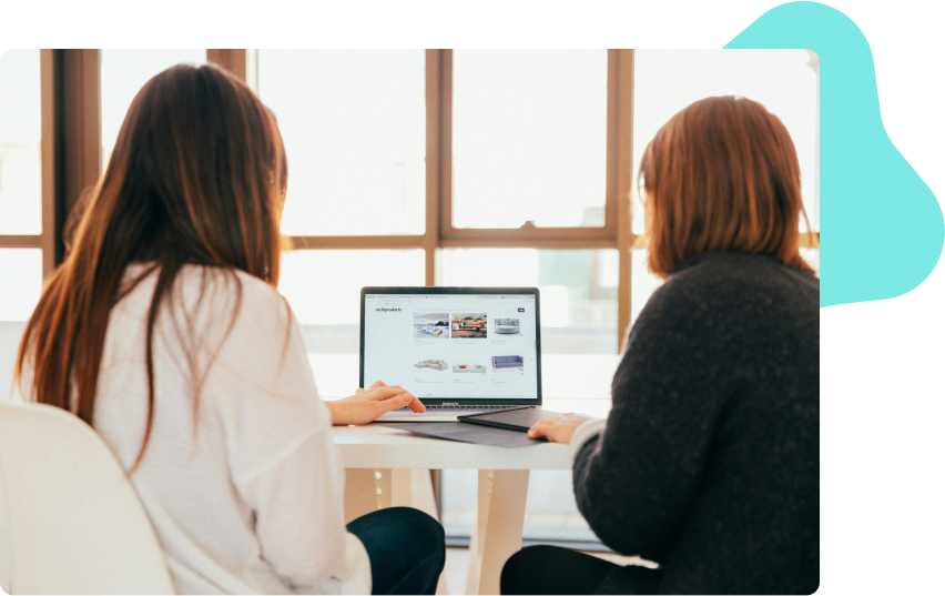 Two people sitting side by side working on a laptop with website screens in the viewport