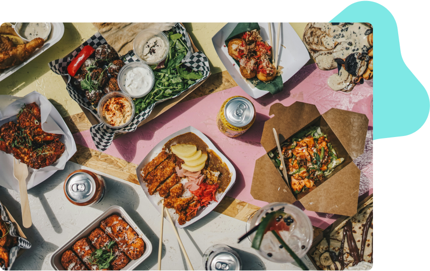 A birds eye view of a table filled with food in to go dishes and drink cans.