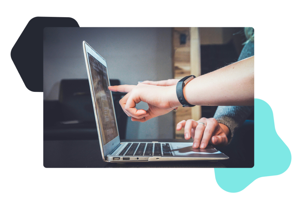 A person out of frame working on a laptop and pointing to something on the screen. 